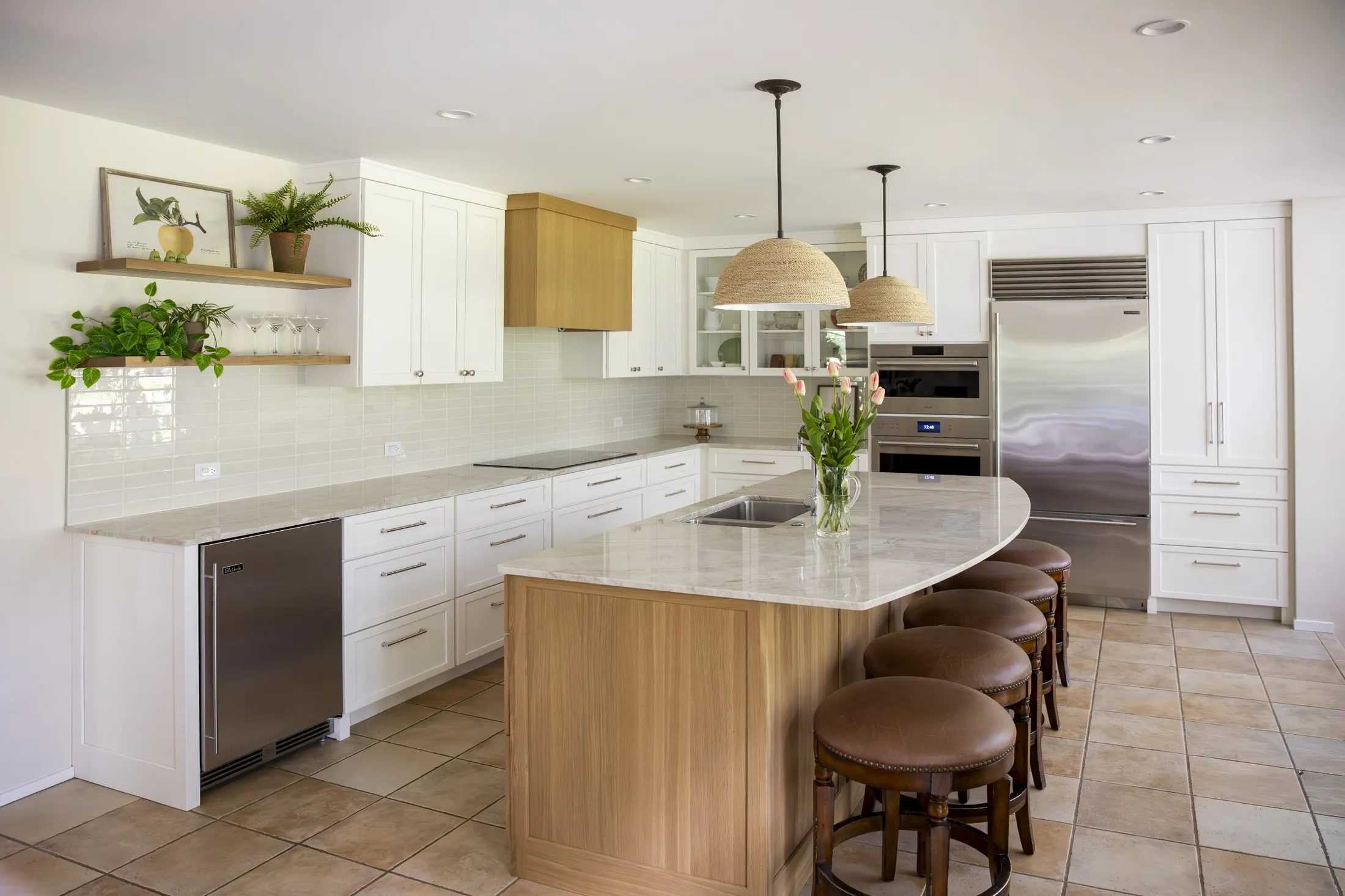 White shaker kitchen with curved oak island, leather stools and rattan pendants